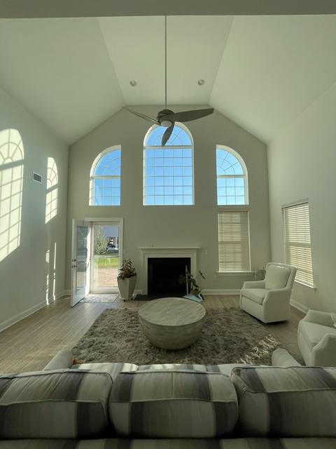 Modern living room with vaulted ceiling, arched windows, fireplace, and contemporary furniture