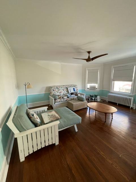 Spacious living room with turquoise accent walls, wooden furniture, and large windows