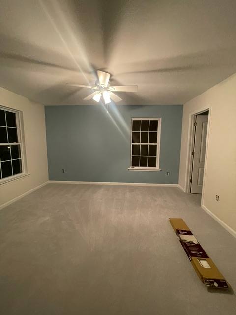 Empty bedroom with blue accent wall, ceiling fan, and flooring materials on floor