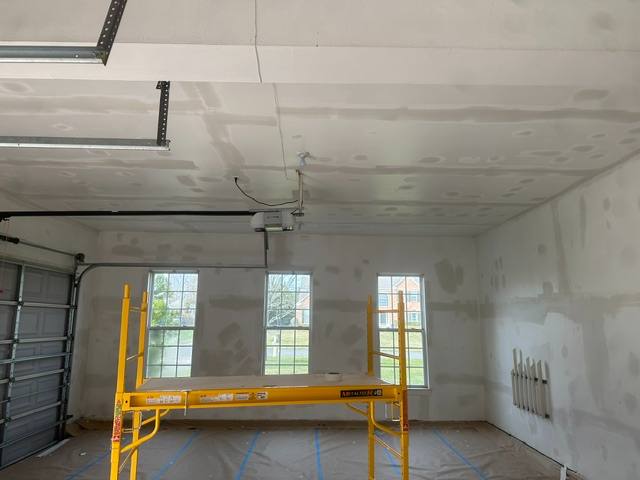 Empty garage under construction with drywall ceiling and yellow work scaffold