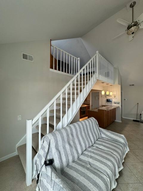 Interior staircase with white railings leading to upper loft in modern home with kitchen visible below