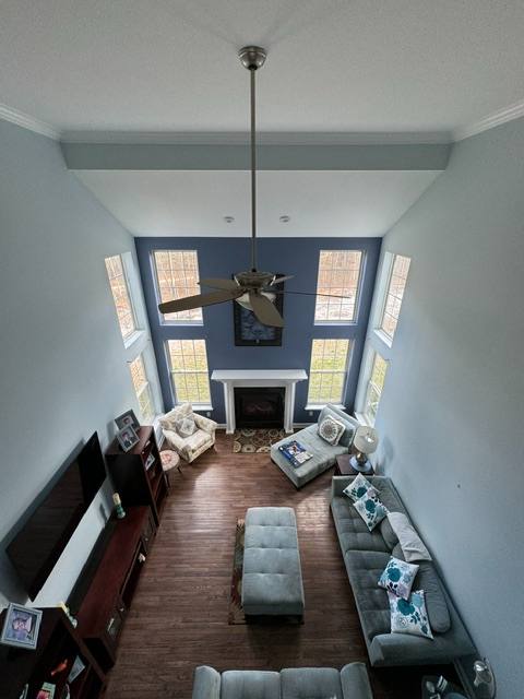 Overhead view of modern living room with two-story ceiling, fireplace, pendant light, and large windows