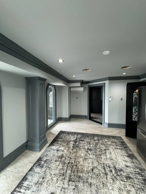 Modern hallway with gray walls, dark trim, recessed lighting, patterned area rug, and multiple doorways