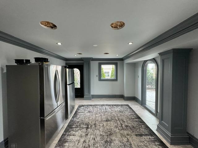 Modern kitchen with stainless steel refrigerator, gray cabinetry, recessed lighting, and glass doors