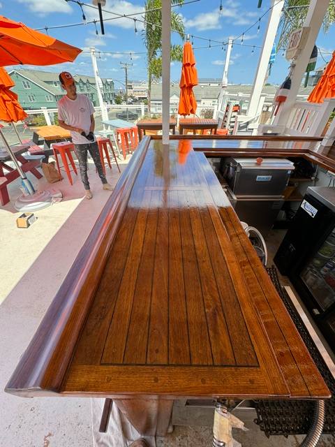 Long wooden table on outdoor rooftop patio with orange umbrellas and city views