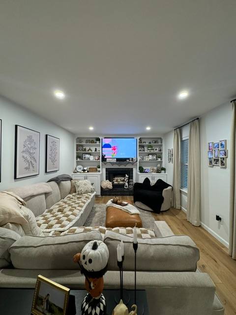 Modern living room with sectional sofa, fireplace, wall shelving, and TV entertainment center