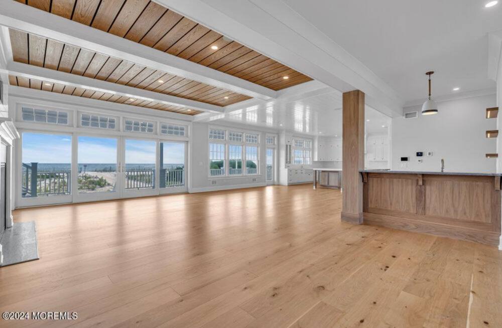 Modern open-concept living space with wood flooring, ocean views, and contemporary kitchen with wood cabinetry