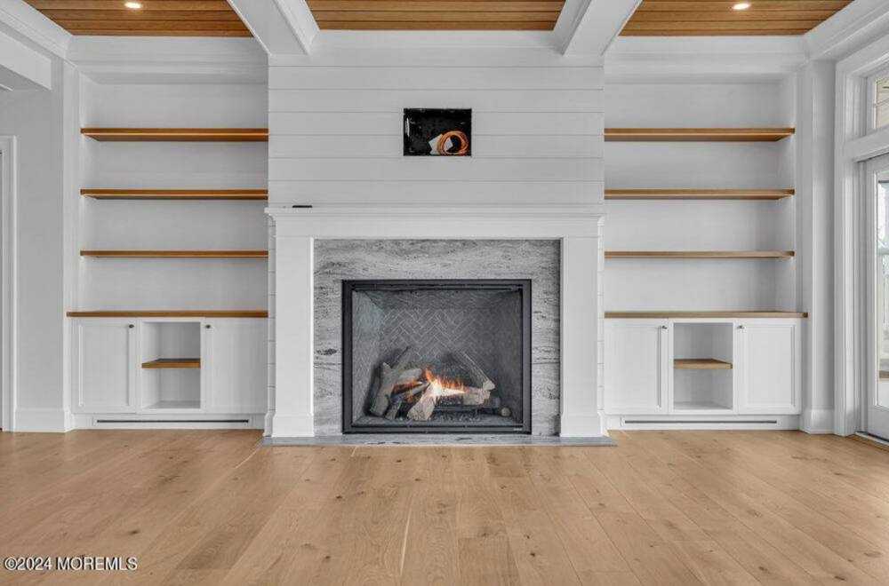 Modern fireplace with white shiplap surround, wooden shelving, and built-in cabinets