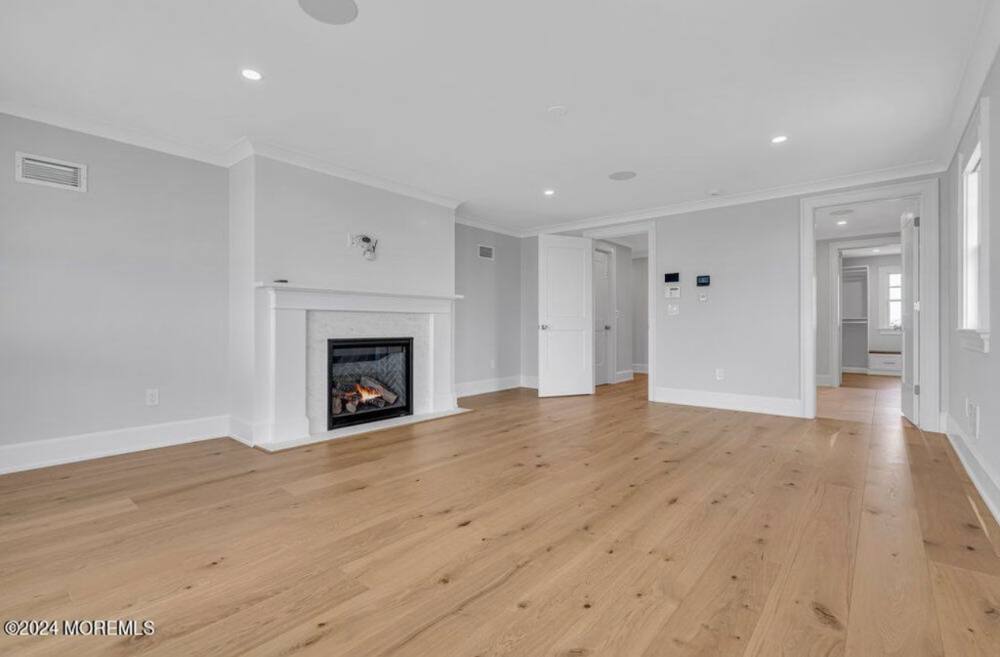 Spacious open living room with fireplace, hardwood floors, and multiple doorways