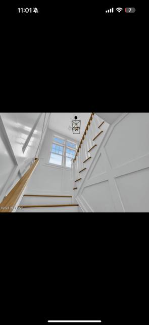 Modern staircase with wooden handrail and white walls viewed from above