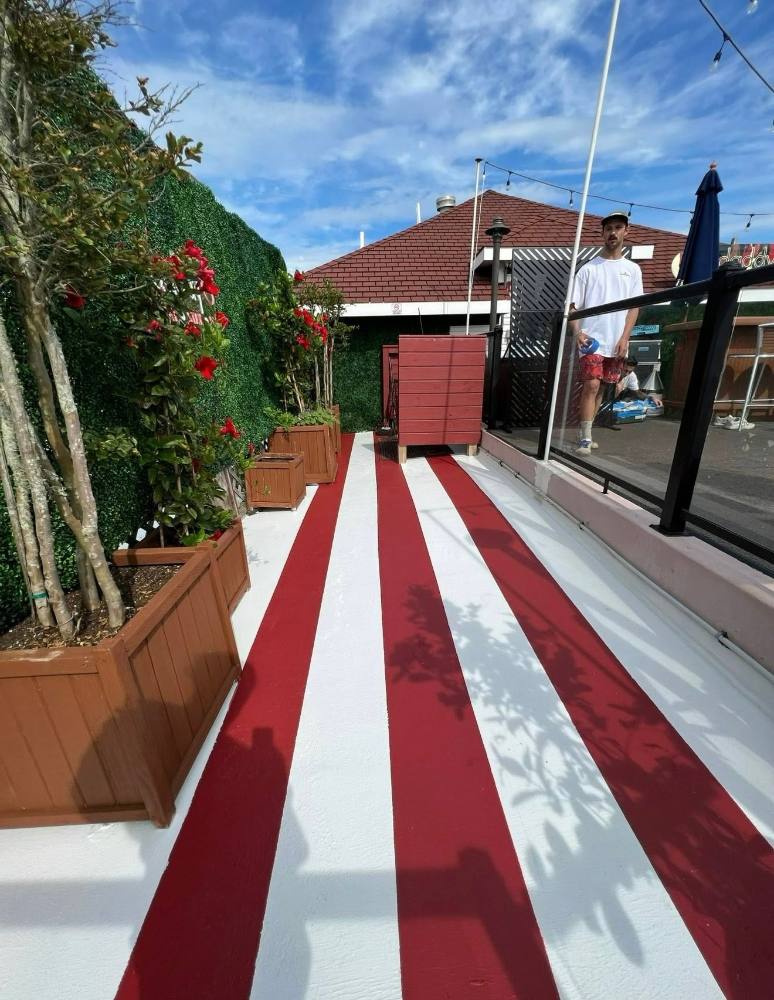 Red and white striped outdoor deck with green ivy wall and flowering planters