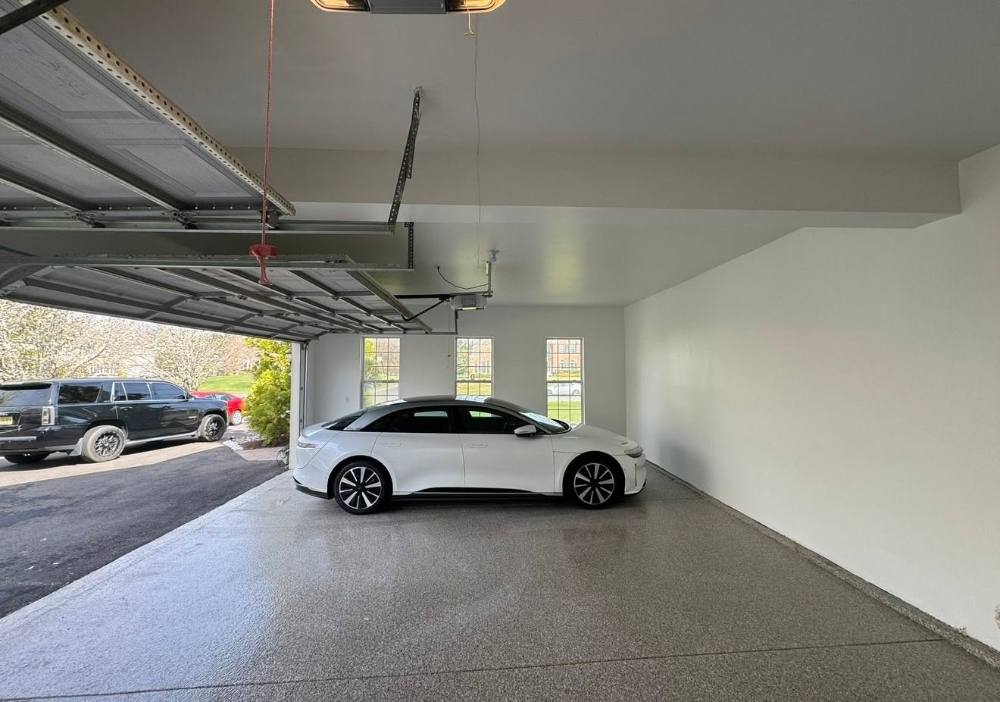 White sedan parked inside modern garage with epoxy flooring and windows