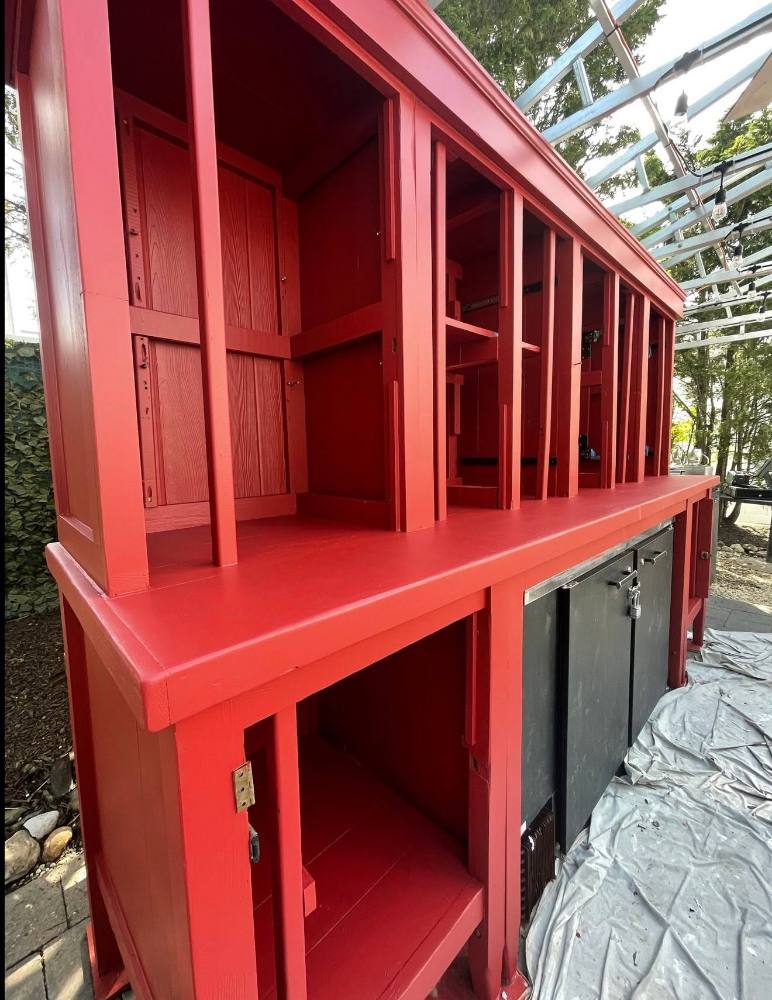 Red two-story structure with multiple wooden doors and open compartments