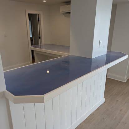 Modern kitchen island with dark countertop and white paneled base in open concept space