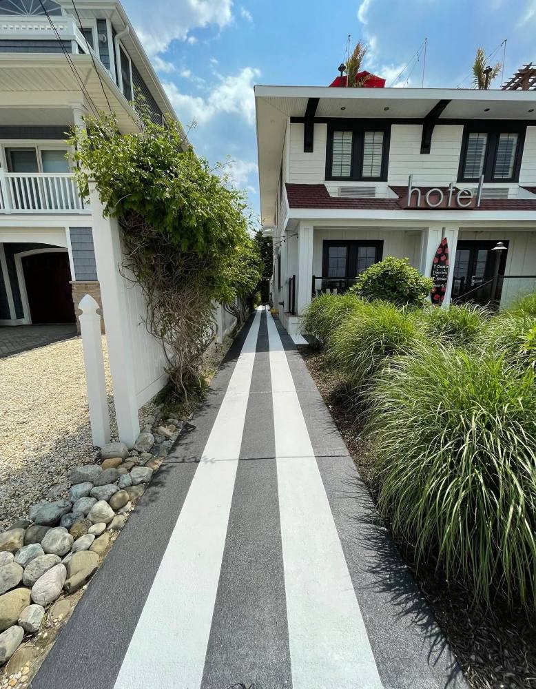 Striped walkway between white residential building and hotel with landscaping