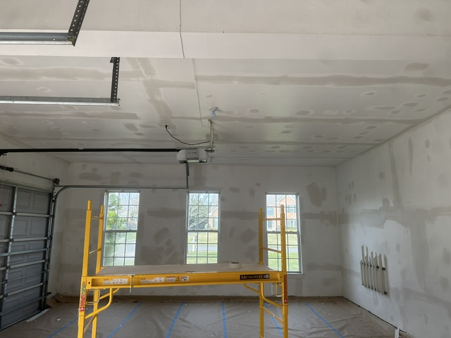 Interior construction space with drywall ceiling, yellow scaffolding, and three windows