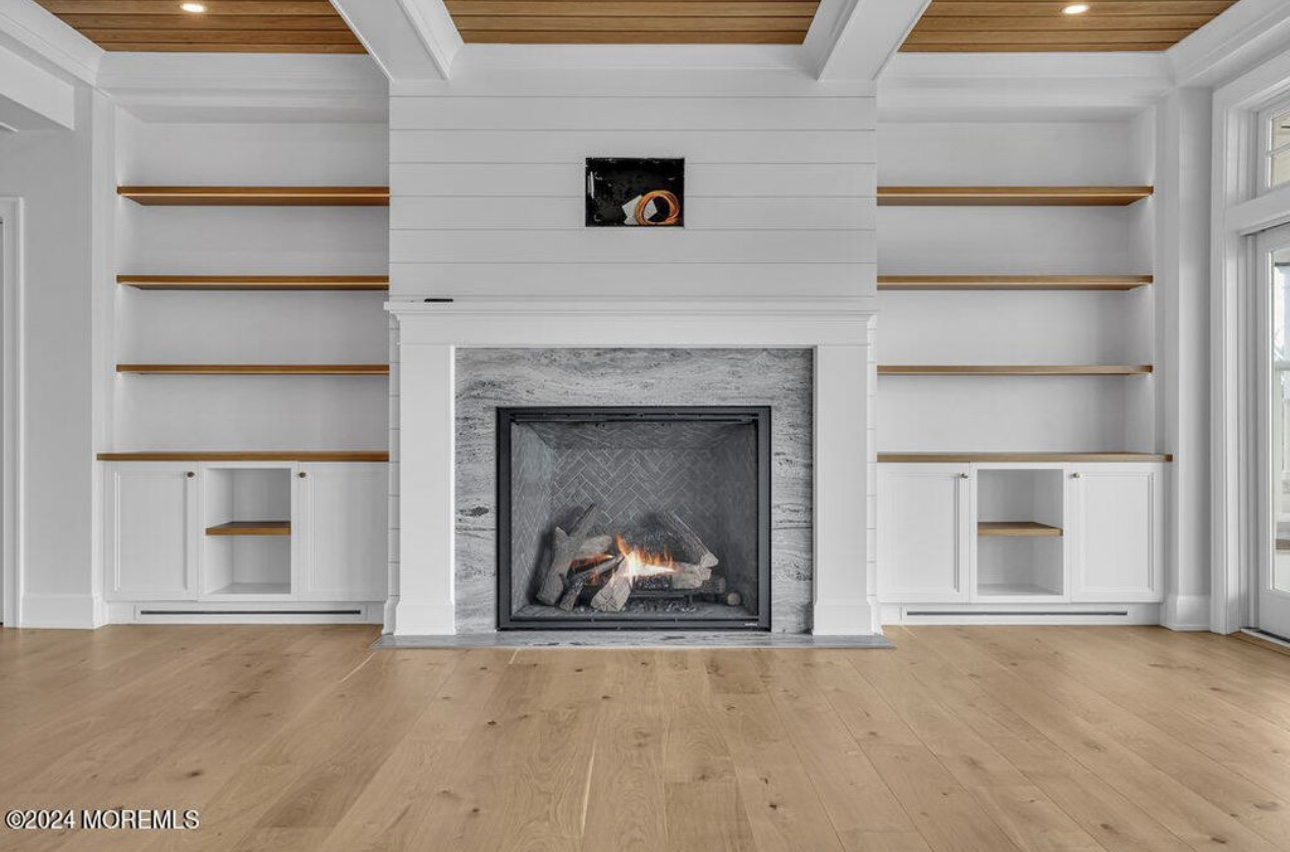 Modern fireplace with white shiplap surround, gas insert, and built-in shelving with wooden accents